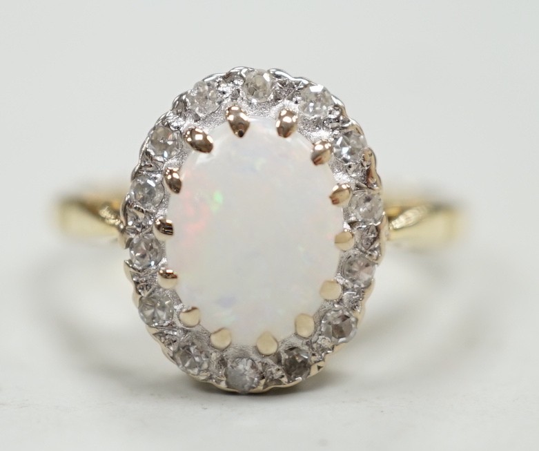 A modern 18ct white gold white opal and diamond set oval cluster ring, size M, gross weight 4.3 grams.